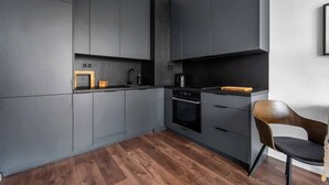 Une cuisine moderne avec des meubles de couleur gris foncé, un plancher en bois et une chaise noire.