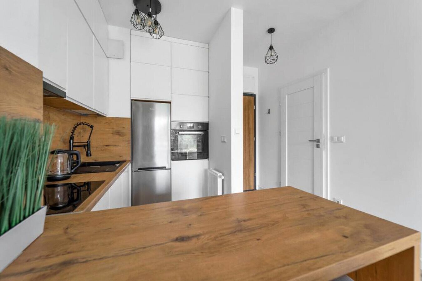 Een moderne keuken met witte kasten, een roestvrijstalen koelkast en een houten aanrecht.