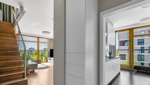 Un apartamento moderno con escalera de madera, cocina con vistas y balcón con vista panorámica de la ciudad.