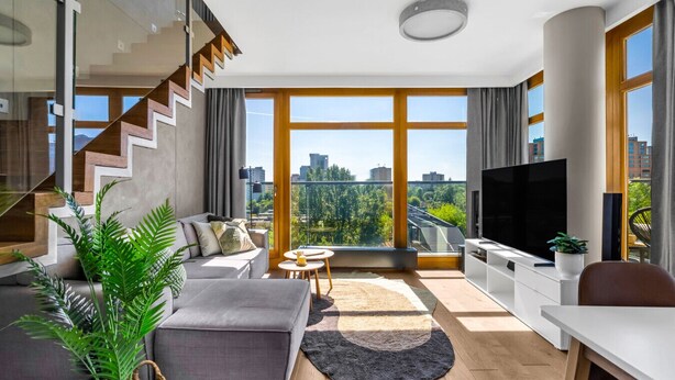 Una sala moderna con sofá, televisor y vistas a la ciudad.