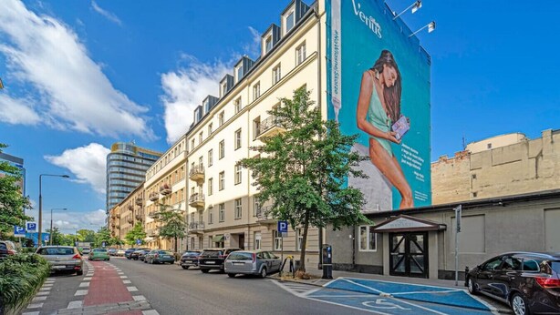 Straßenansicht mit einem Gebäude, das eine große Werbung an seiner Seite zeigt.
