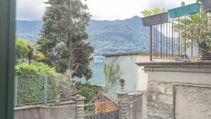 A view of a mountainous landscape with a body of water, a tall tree, and a metal fence. - Nonna Tere Apartment (Carate Urio)