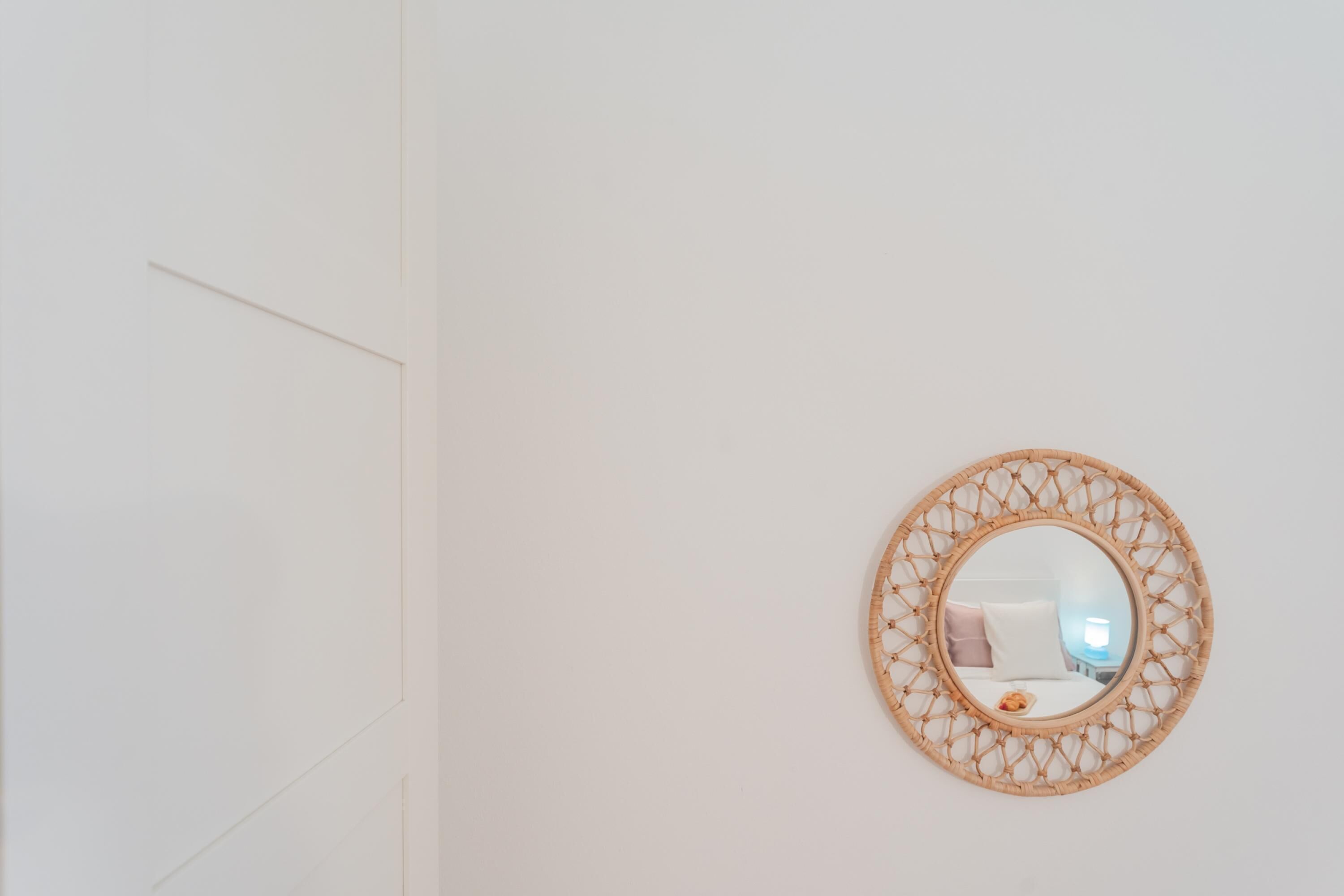 A wall with a circular mirror framed in a woven pattern.