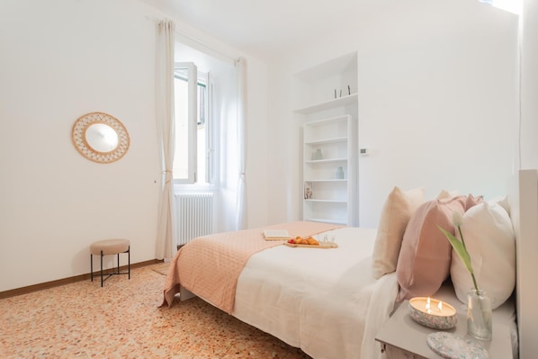 Een slaapkamer met een bed, nachtkastje en een raam.
