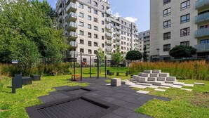 Un espace extérieur moderne comprenant une aire de jeux, des sièges et une grille d’évacuation des eaux.