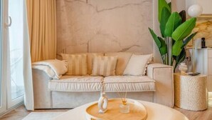 Ein stilvolles Wohnzimmer mit einem weißen Sofa, einem runden Couchtisch und einer großen Pflanze.