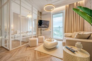 Una sala de estar moderna con un televisor grande, asientos cómodos, una mesa redonda y vistas al exterior.