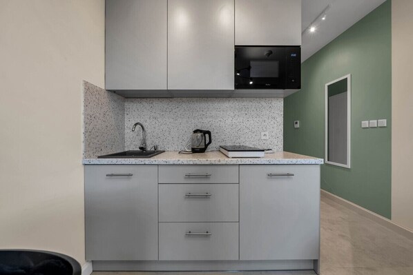A modern kitchen with a microwave, kettle, and kettle on the countertop.
