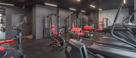A modern gym with various exercise equipment, including treadmills, stationary bikes, and weight machines.