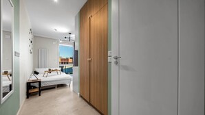 Une chambre moderne avec un lit, des tables de chevet, une armoire et une vue sur le paysage urbain par la fenêtre.