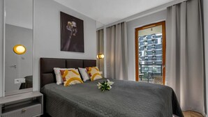 Habitación de hotel moderna con una cama grande, una mesita de noche, un espejo y vistas a la ciudad a través de la ventana.