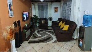 A living room with a sofa, TV, and a water dispenser. - Casa Villa Diani (Diani Beach)