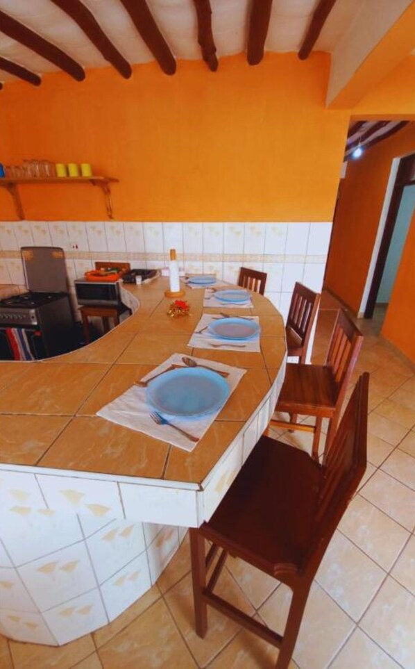 A kitchen with a curved island, wooden chairs, and a tiled backsplash.