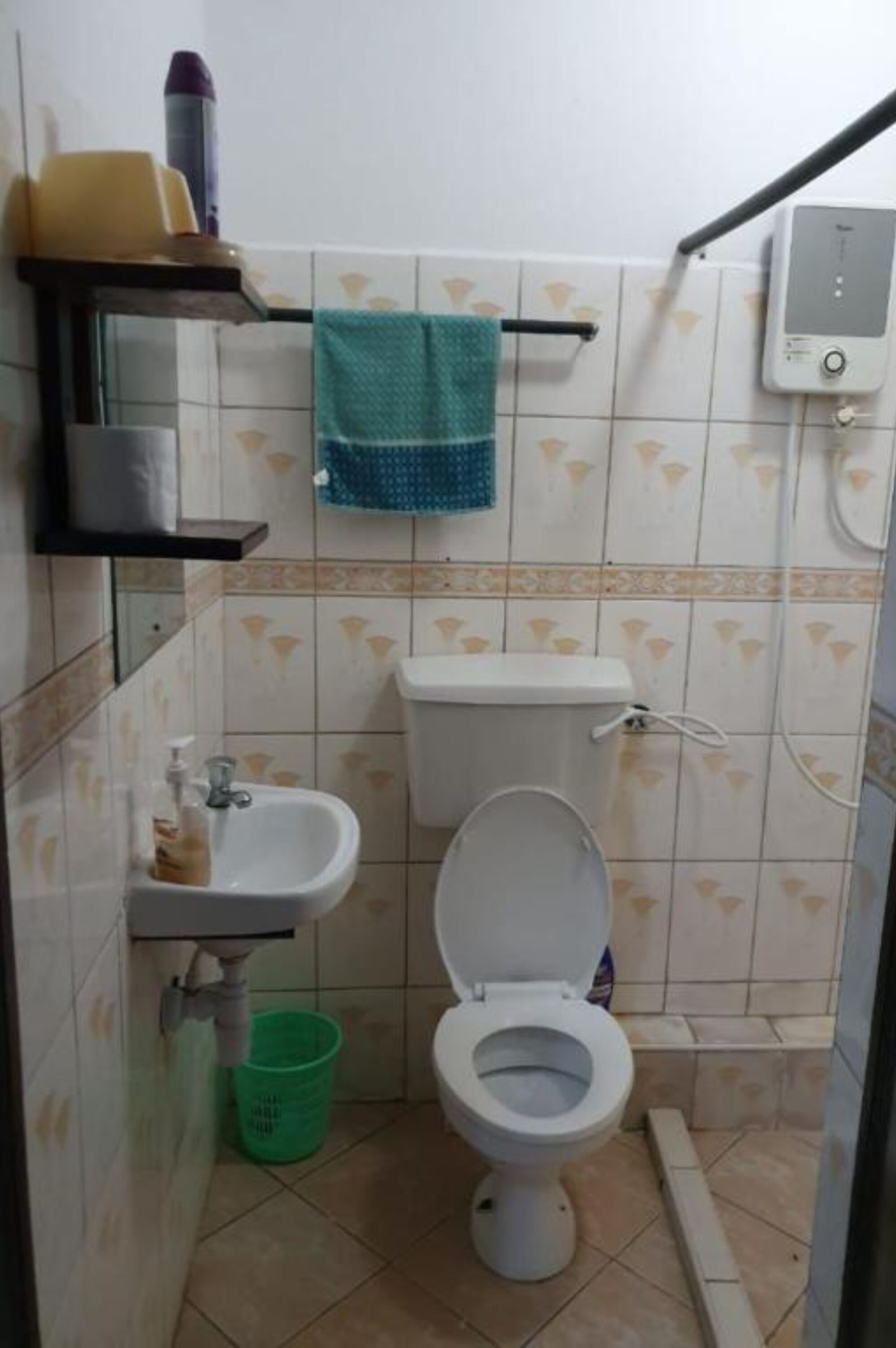 A small bathroom with a toilet, sink, and a green trash bin.