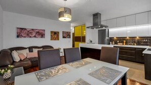Un salon moderne avec une table à manger, un canapé et des œuvres d’art accrochées aux murs.