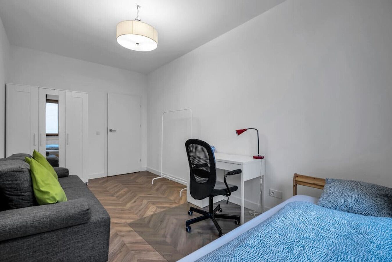 A compact room with a bed, a desk, a chair, and a sofa.