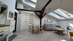 A modern loft apartment with skylights, a dining area, a sofa, and a kitchen. - Kraków Comfort Loft Apartments by Rentujemy (Kraków)