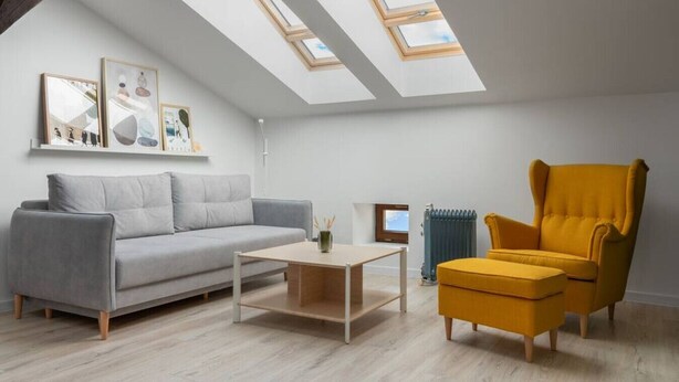 A modern living room with a grey sofa, a yellow armchair, a coffee table, and a skylight. - Kraków Comfort Loft Apartments by Rentujemy (Kraków)