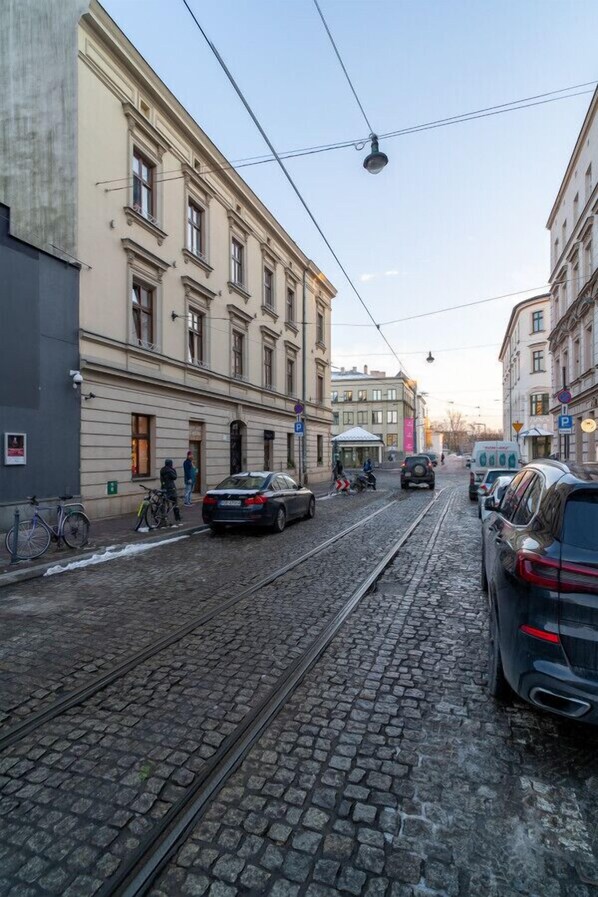 A street with tram tracks, parked cars, and buildings with classical architecture.