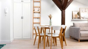 A dining area with a white table and chairs, a wooden ladder shelf, and a grey sofa. - Kraków Comfort Loft Apartments by Rentujemy (Kraków)