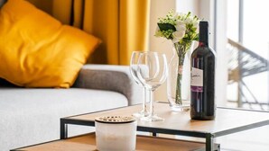 Un salon moderne avec un canapé, une table basse, une bouteille de vin et un vase rempli de fleurs.