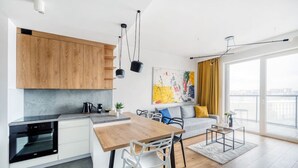 Une cuisine moderne avec des meubles en bois, un four encastré et un coin repas comprenant une table et des chaises.