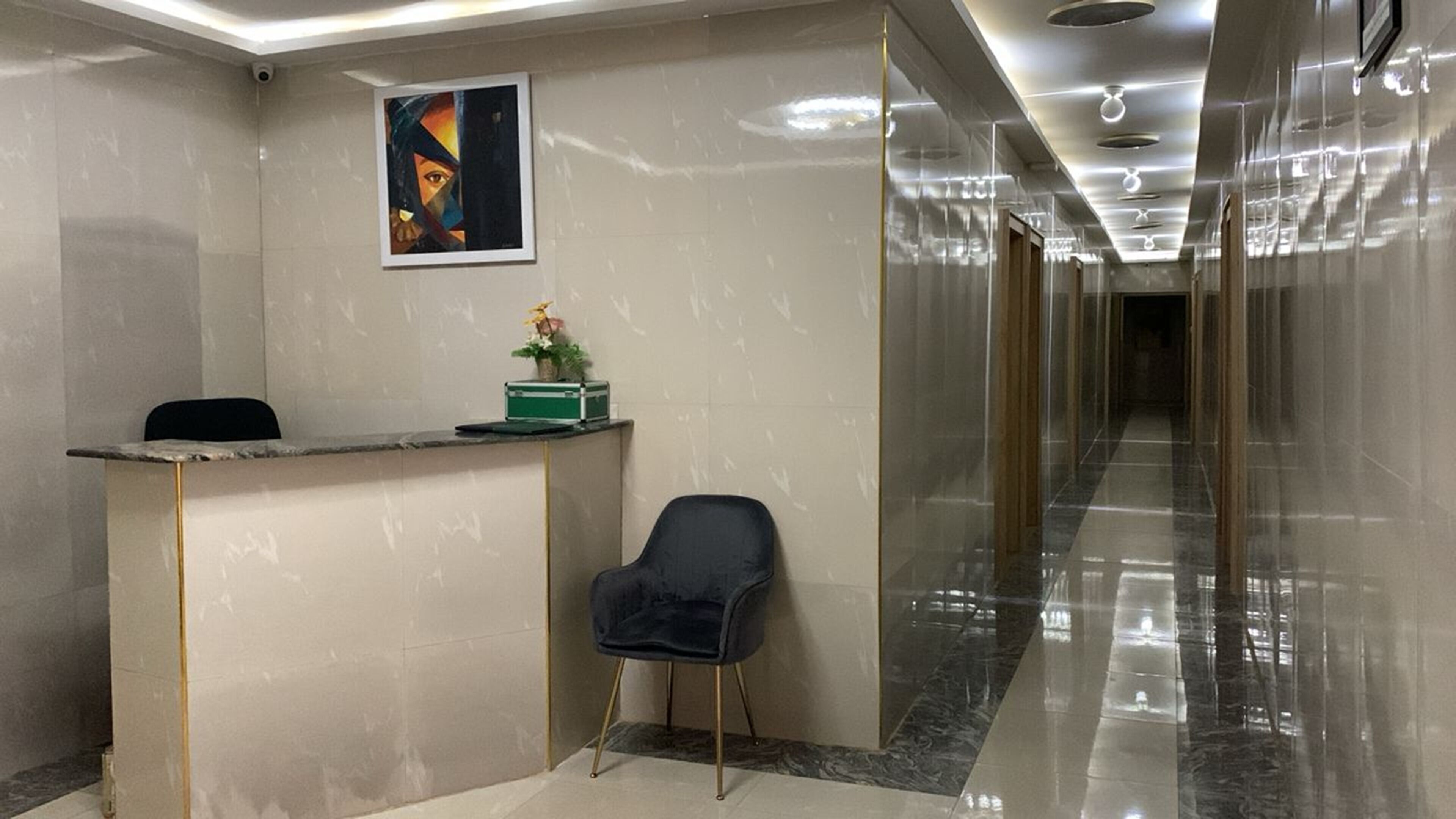 A reception area with a marble counter, a black chair, and a framed artwork on the wall.