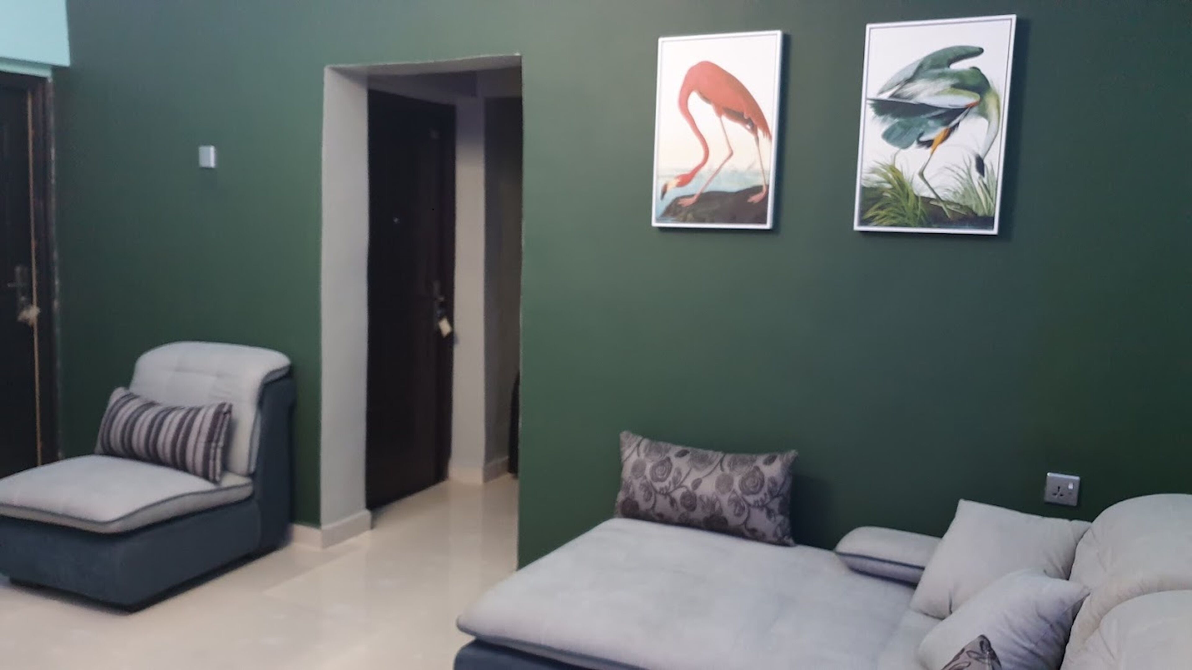 Una stanza con un letto, una sedia e due dipinti di uccelli appesi al muro.