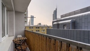 Een balkon met uitzicht op moderne gebouwen, waaronder een hoge wolkenkrabber.