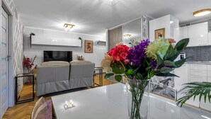 Een moderne woonkamer met een bank, een eettafel en een bloemenvaas.