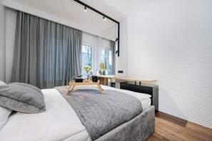 Ein modernes Schlafzimmer mit einem großen Bett, einem Nachttisch, einem Schreibtisch und einem Fenster mit Vorhängen.