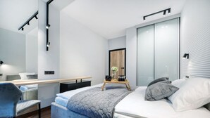 Un dormitorio moderno con cama, mesita de noche, silla y un espejo grande.