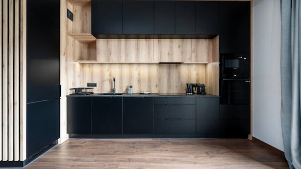 Una cocina moderna con gabinetes negros, una encimera de madera y un microondas integrado.