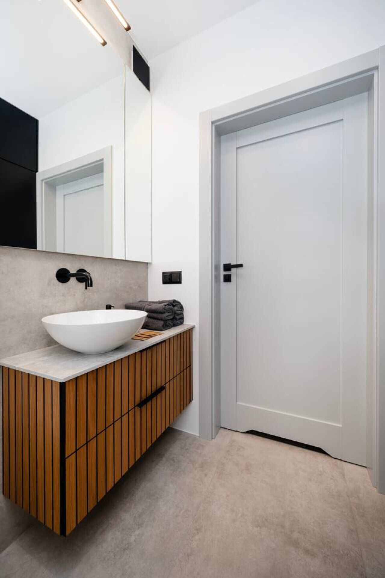 Une salle de bain moderne avec un grand lavabo blanc, un meuble-lavabo en bois et une porte blanche.