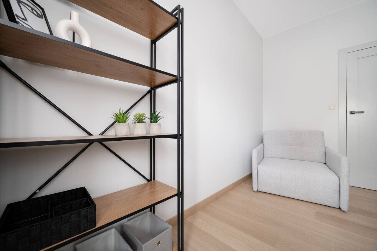 Een moderne kamer met een ingebouwd houten wandrek, een grijze bank en een witte deur.