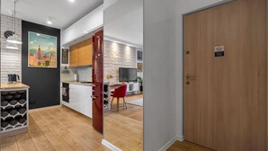 A modern kitchen with white cabinets, a red wine rack, and a wooden door. - Warsaw Wola - Parking & Balcony - by Rentujemy (Warszawa)