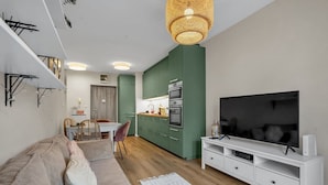 A modern living room with a sofa, a TV, and a dining area with a table and chairs.