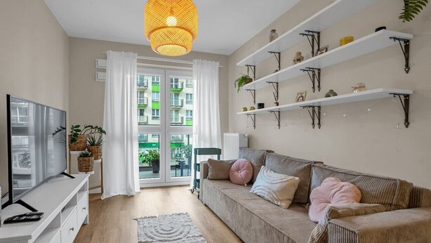 A modern living room with a sofa, TV, and shelves.