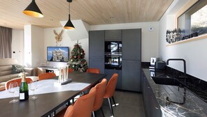 A modern kitchen with grey cabinets, a built-in oven, and a black countertop.