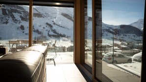 A room with large windows offering a view of a snowy mountain landscape and parked cars outside.