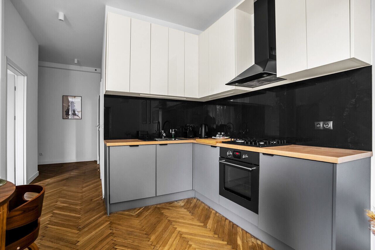 Una cocina moderna con armarios grises, encimera negra y suelo de madera en patrón de espiga.
