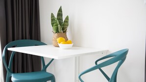 Una pequeña mesa con una cesta tejida que contiene una planta y un cuenco de limones, flanqueada por dos sillas color turquesa.