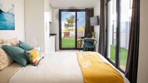 Habitación de hotel con cama, televisor, balcón con mesa y sillas, y vista al exterior.