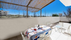 A covered outdoor dining area with a table set for two, white chairs, and a view of the surrounding landscape. - 3835 Summer House by Barbarhouse (Porto Cesareo)