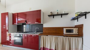 A compact kitchen with red cabinets, a microwave, and a wooden countertop. - 3835 Summer House by Barbarhouse (Porto Cesareo)