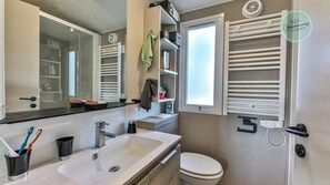 A modern bathroom with a sink, mirror, towel rack, and toilet.
