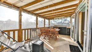 A covered outdoor area with wooden flooring, a table with chairs, and a grill. - Mobil-home dans parc résidentiel (Saint-Hilaire-de-Riez)