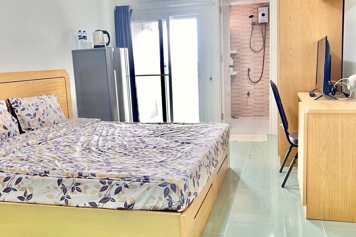 A hotel room with a bed, a desk, a chair, a shower, and a toilet.