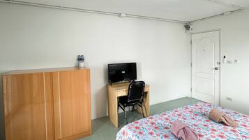 A bedroom with a bed, a desk with a chair, a wardrobe, and a television.