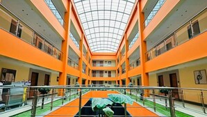 A multi-level atrium with a glass ceiling, green artificial turf, and a central water feature. - The Radiant Swan (Vagra)